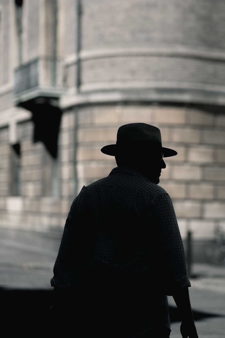 silhouette photo of a man with hat standing near concrete building at daytime, man wearing hat and dress standing in front of a high rise building HD wallpaper