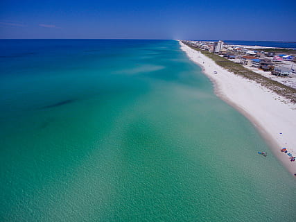 coastline near building, white sand beach near body of water under blue sky at daytime HD wallpaper