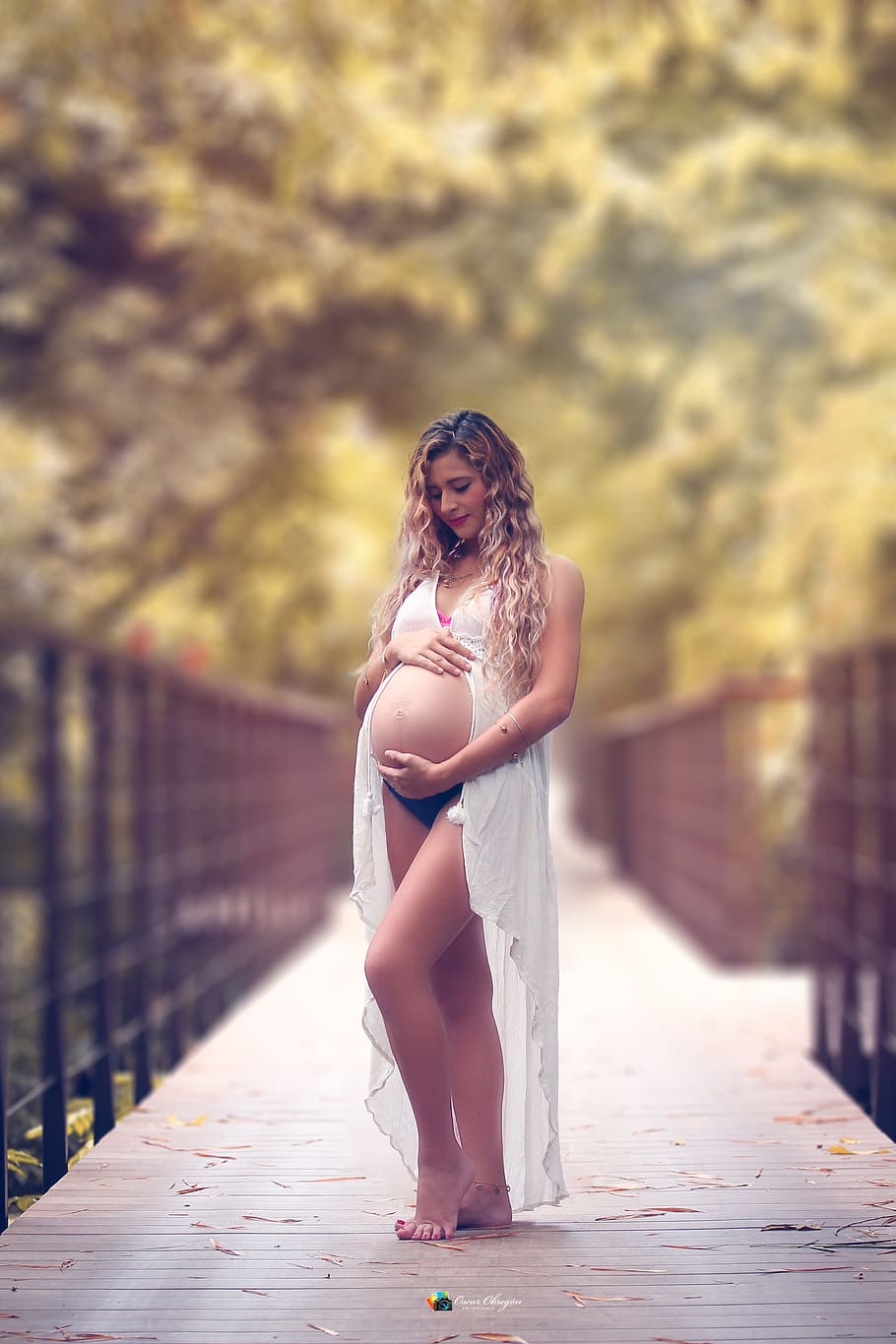 pregnant woman holding her tummy standing on bridge, maternity