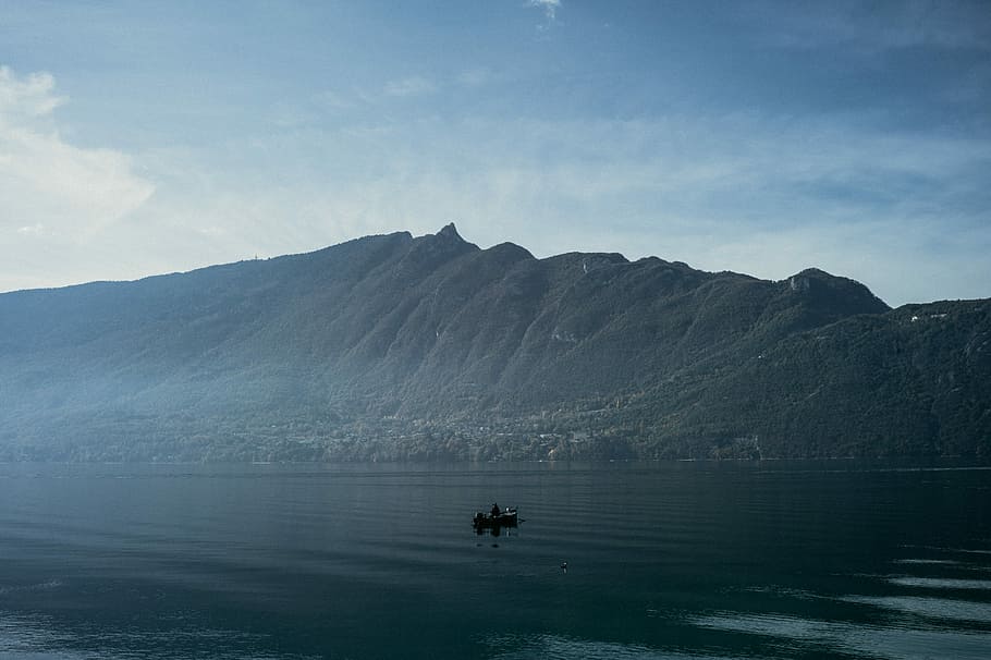 person on board on body of water near mountain during daytime, body of water and mountain ahead HD wallpaper