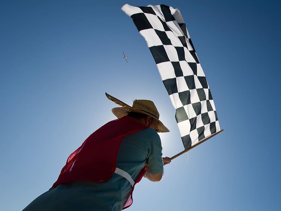 man carrying black and white checkered flag, race, aircraft, sky