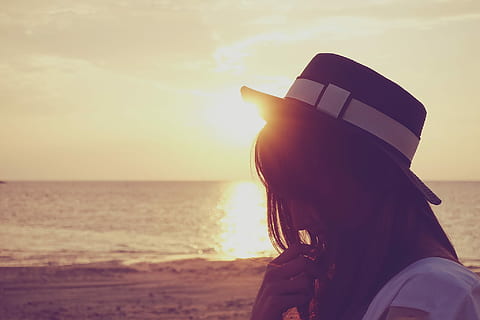 woman in white shirt wearing fedora hat near sea shore during sunset HD wallpaper