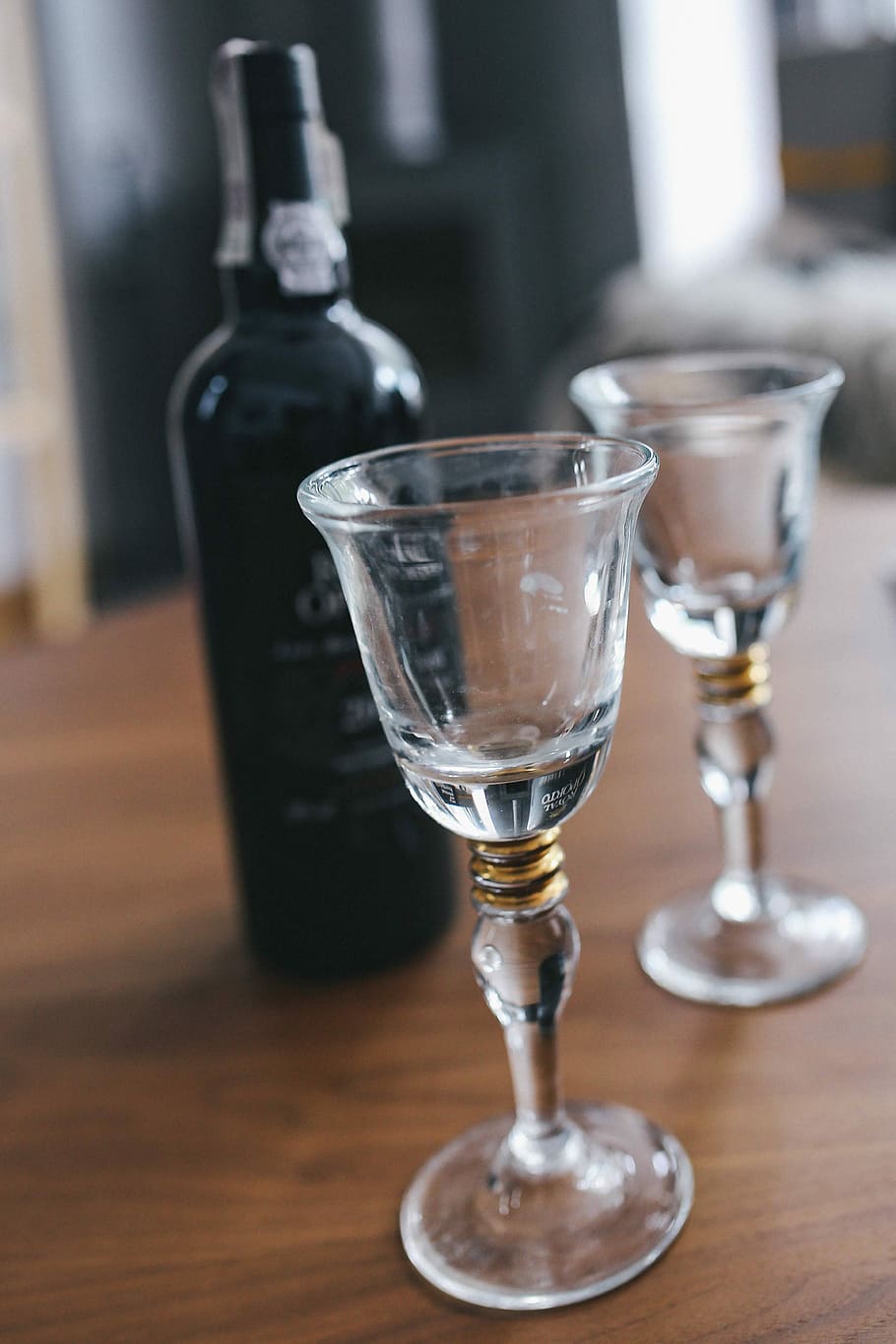Two empty wine glasses with a bottle of wine on a table, alcohol