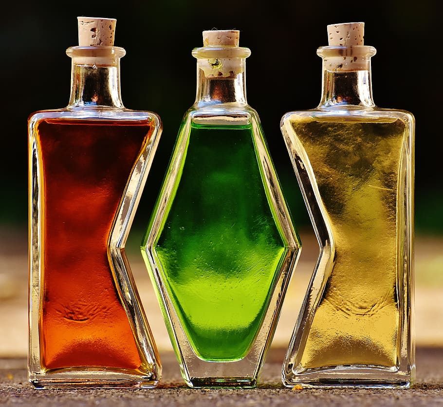 three clear glass bottles with yellow, green, and red liquids HD wallpaper