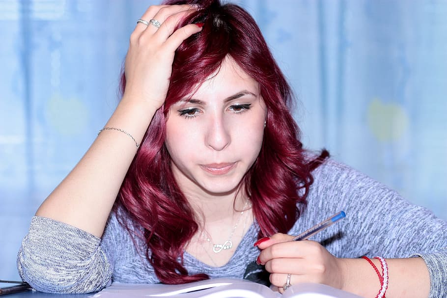 woman wearing gray space-dyed scoop-neck sweatshirt holding blue ballpoint pen while reading a book HD wallpaper