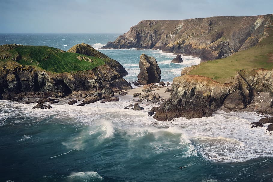 photo of sea waves and boulders, body of water near mountain during daytime HD wallpaper