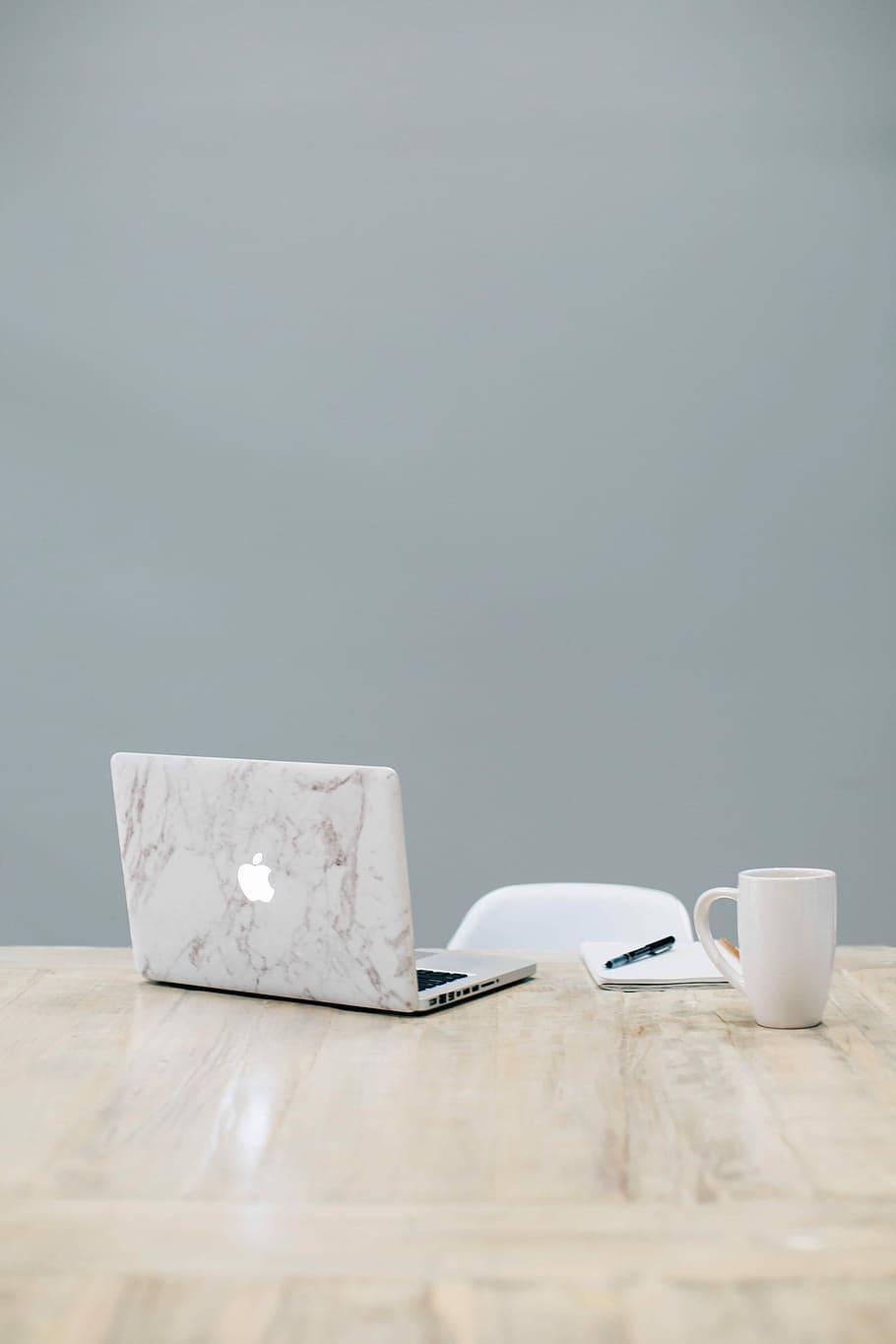 MacBook on table near mug, MacBook Air beside black pen on white notebook and white ceramic cup HD wallpaper