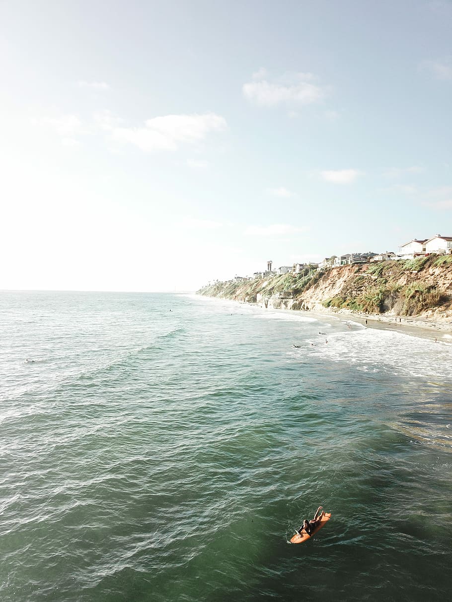 surfing, person laying down on surfboard on sea during daytime HD wallpaper