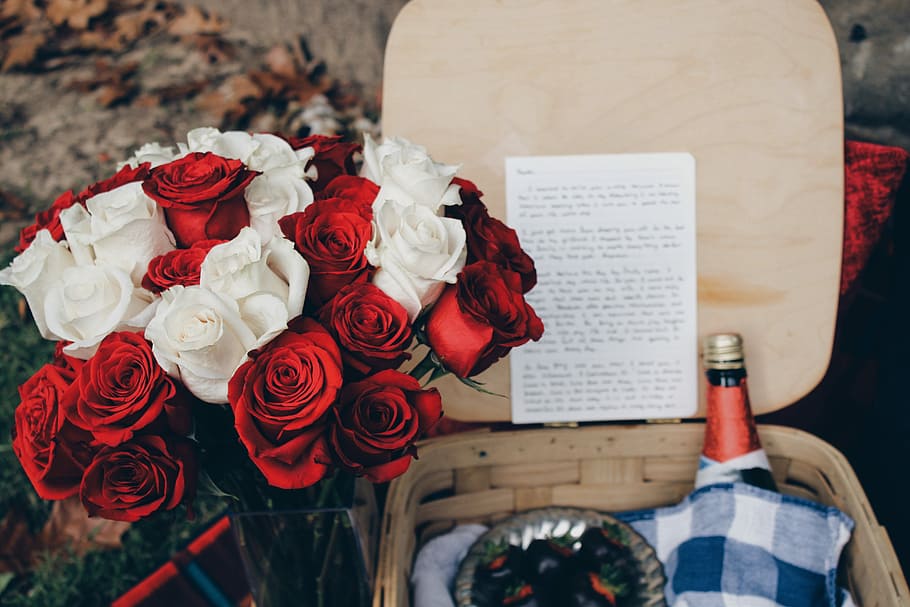 red and white roses beside beige wicker basket, white and red roses near brown basket filled with red labeled bottle