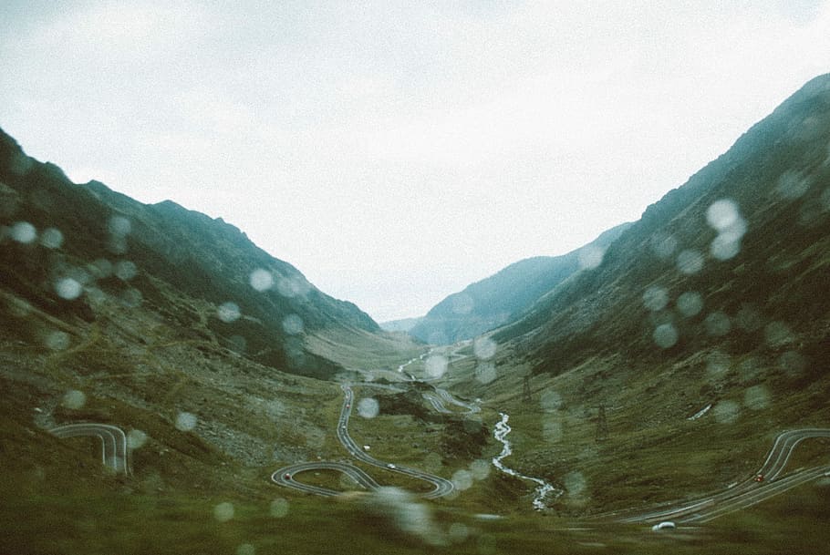 top view of road in between mountains, bokeh photography of green mountains HD wallpaper