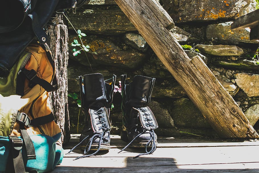 pair of black leather boots beside yellow hiking backpack, gray HD wallpaper