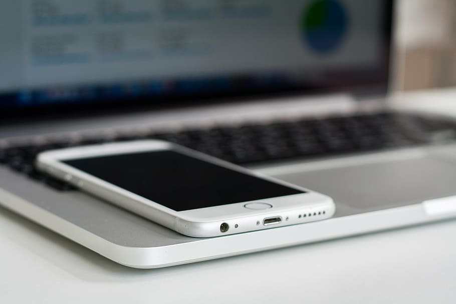 turned-off silver iPhone 6 on top of MacBook Pro, selective HD wallpaper