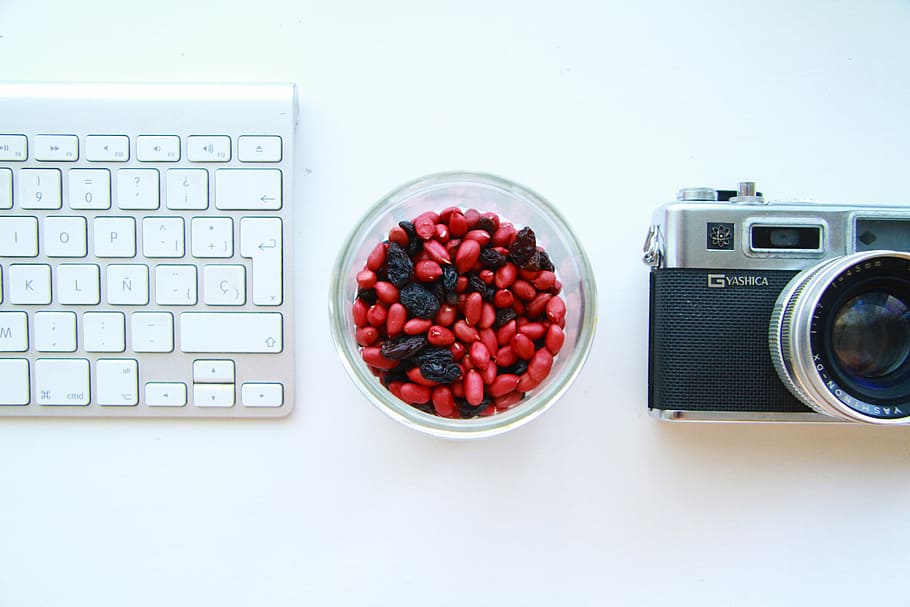 black and gray SLR camera and white keyboard, person taking photo of raisins HD wallpaper