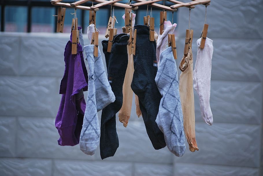 shallow focus photography of assorted socks hanging on brown wooden clothes pin