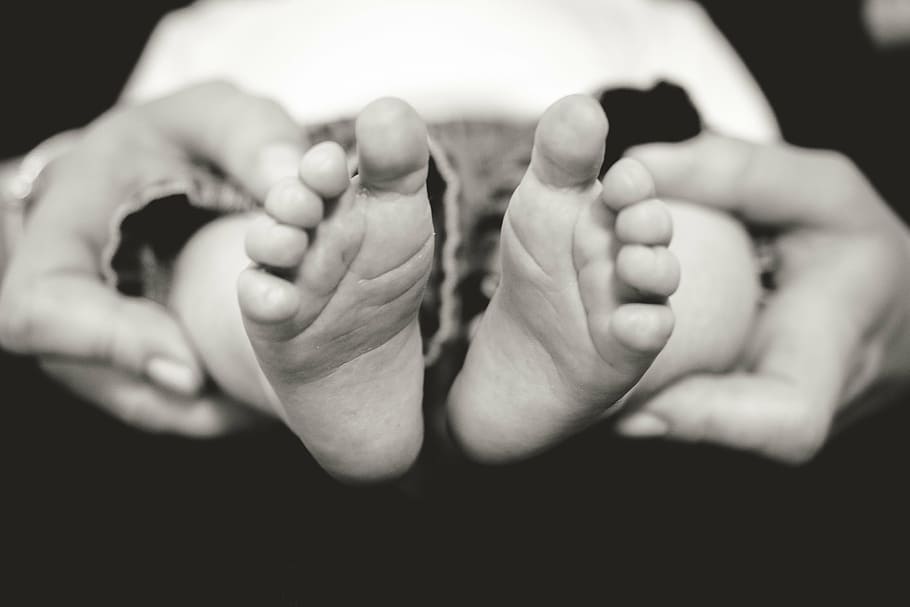 person taking photo to the feet of the newborn baby, grayscale