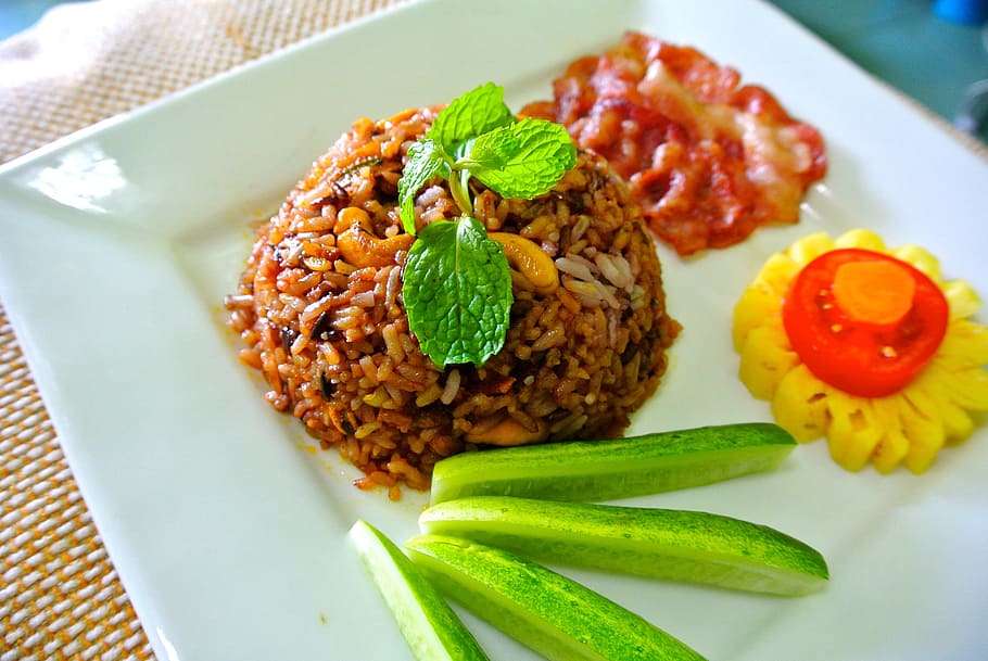 close-up photo of cooked rice with sliced cucumbers and tomato