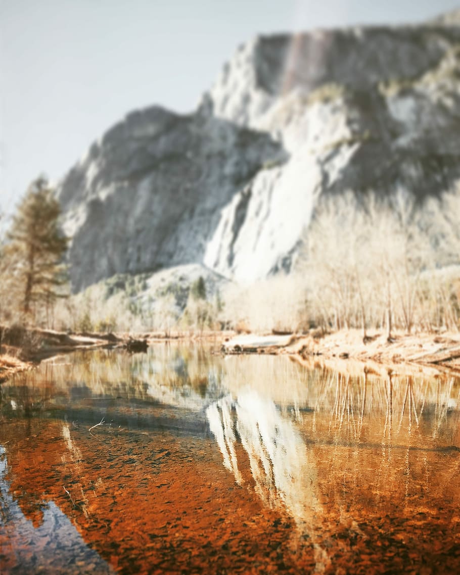 reflection of rock cliff on calm river water, photography of body of water at daytime HD wallpaper