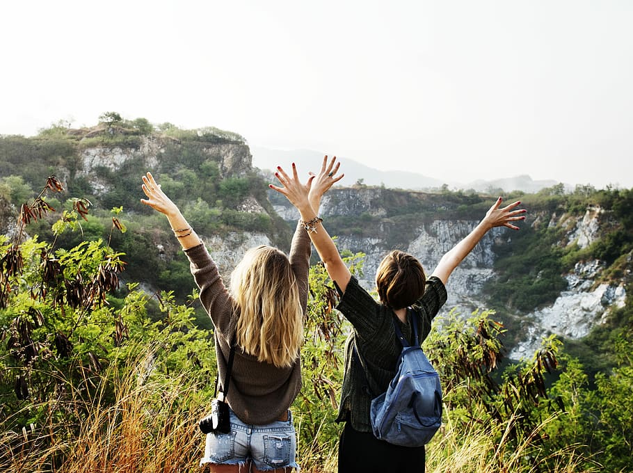 two women raising they're hands, backpack, landscape, adventure HD wallpaper
