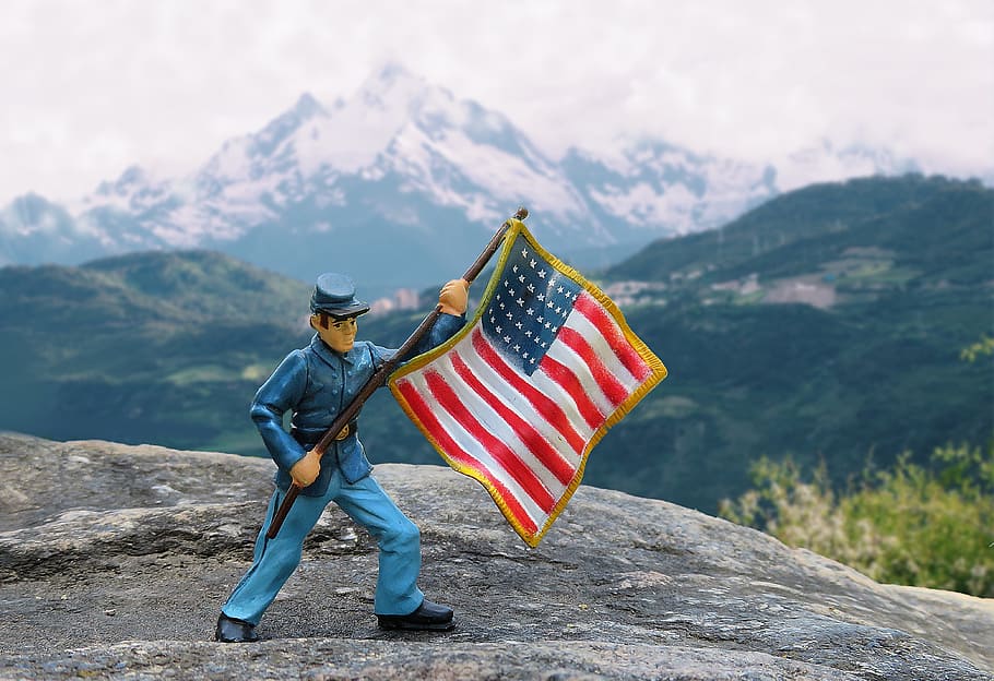 selective focus photography of soldier waving flag of America figurine