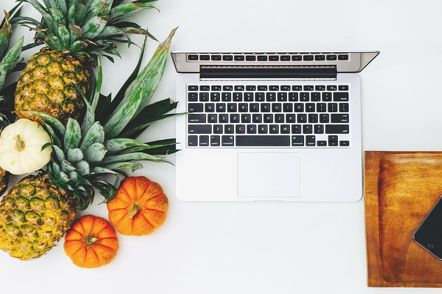 MacBook Pro beside the fruits on the white surface, pineapple HD wallpaper