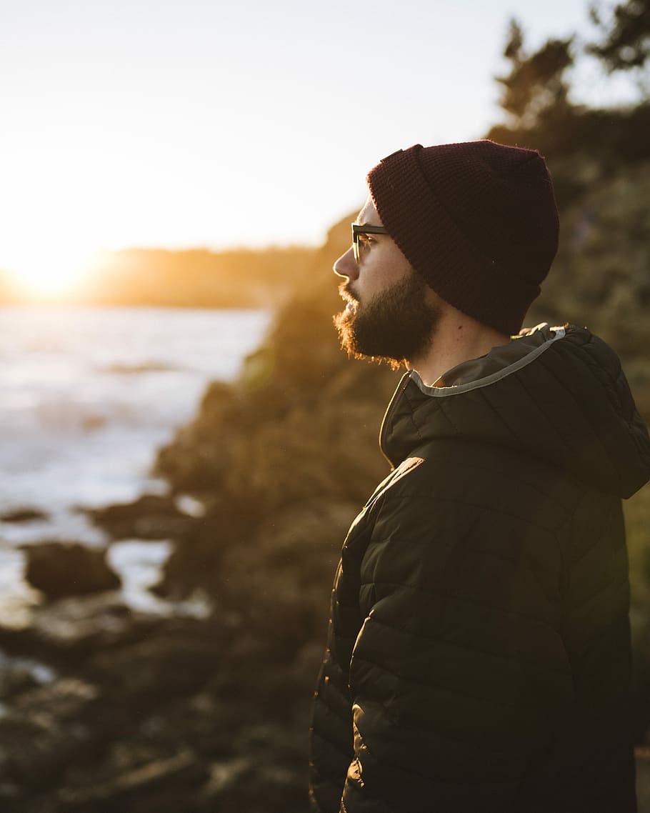man facing sideways standing on sea rocks, man standing near body of water outdoor HD wallpaper