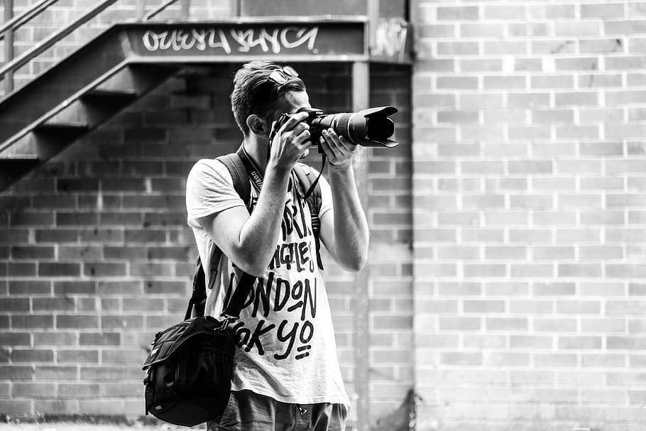 man capturing photograph with DSLR camera standing near stairway, man taking photo HD wallpaper