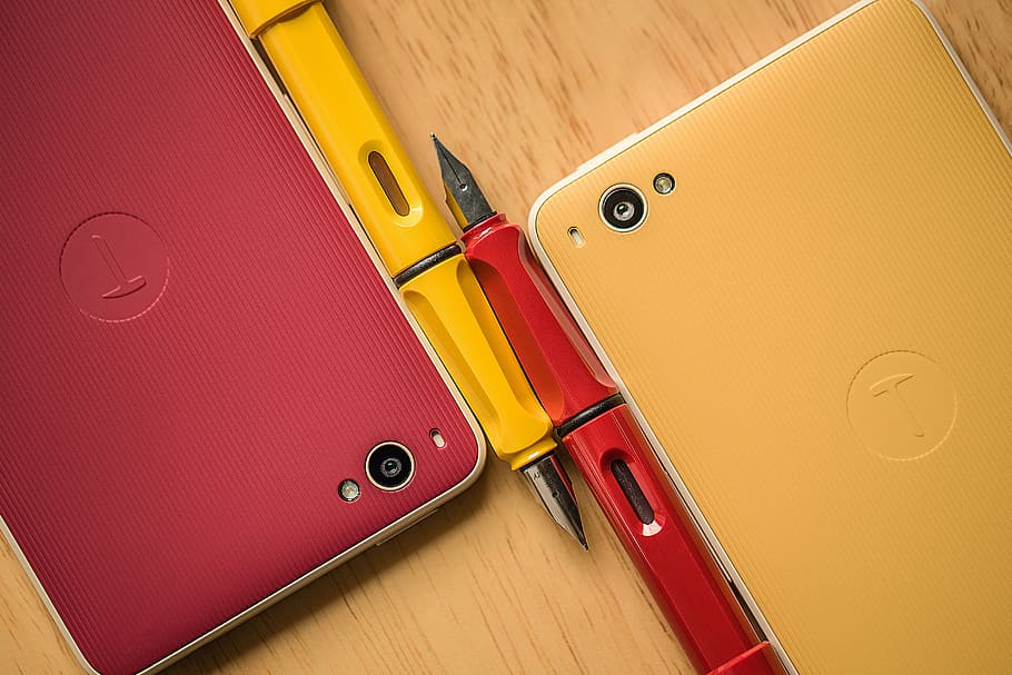 two smartphones beside fountain pens, red, yellow, technology HD wallpaper