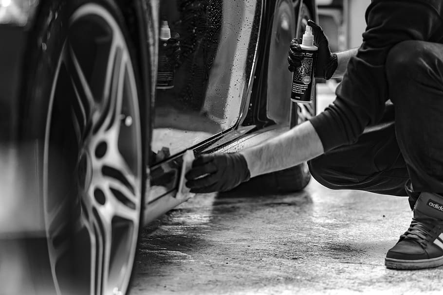 grayscale photography of man cleaning side skirts of car, steam