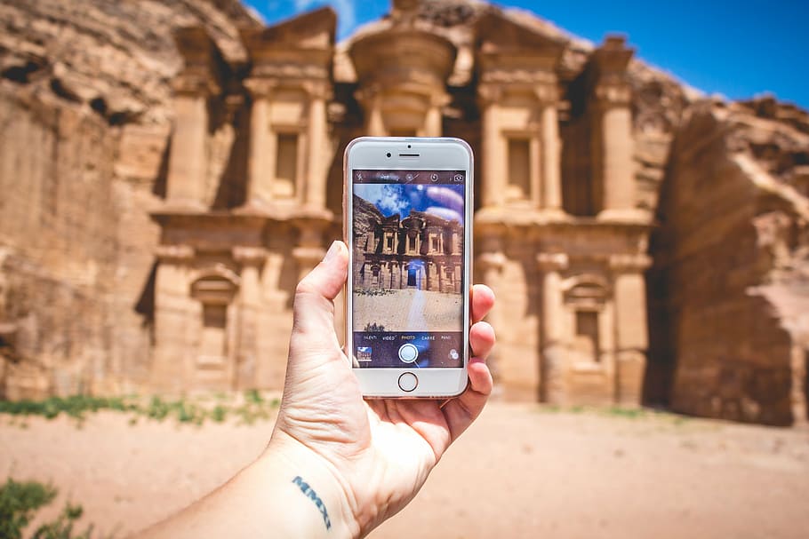 person holding gold iPhone 6 near beige concrete sculpture at daytime HD wallpaper