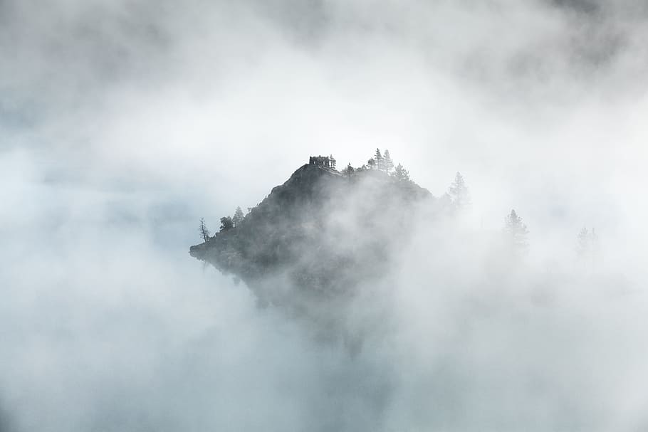 Mountain peak in Emerald Bay peeks through morning mist, foggy photo of island