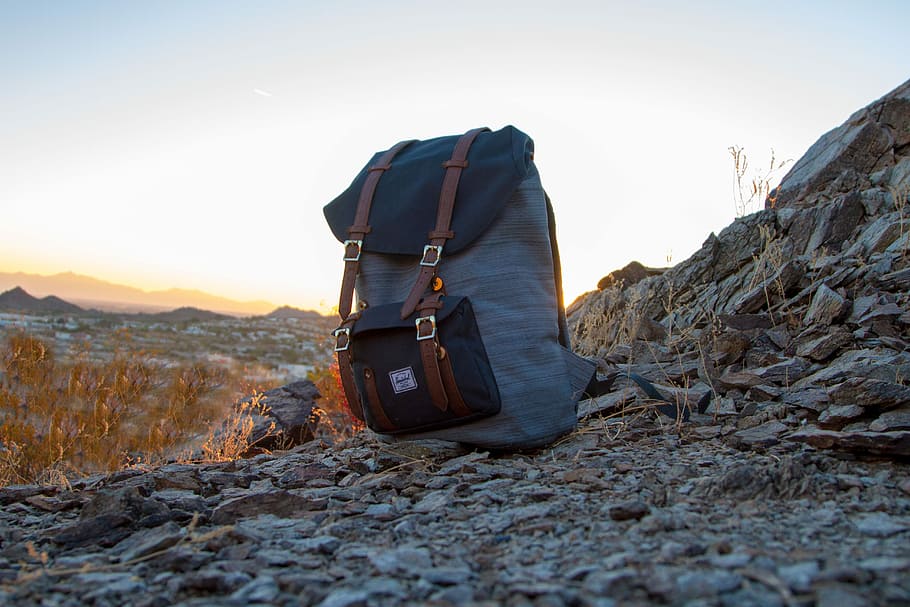 gray and black backpack on top of cliff, gray and black backpack on gray rocks against light at daytime HD wallpaper