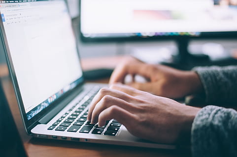 person using black and white laptop computer during daytime HD wallpaper
