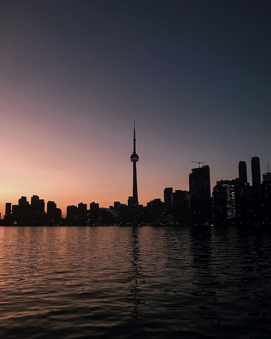 body of water surrounded by buildings under gray sky during sunset, silhouette photography of city skyline HD wallpaper