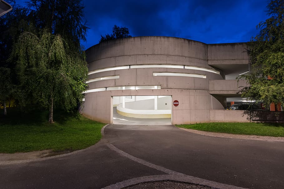photography of gray concrete building at night time, photo of white parking area beside trees HD wallpaper