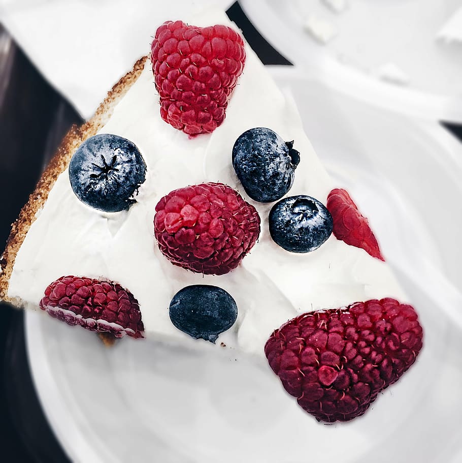 sliced white icing-covered cake with berries on top, cream, sponge cake