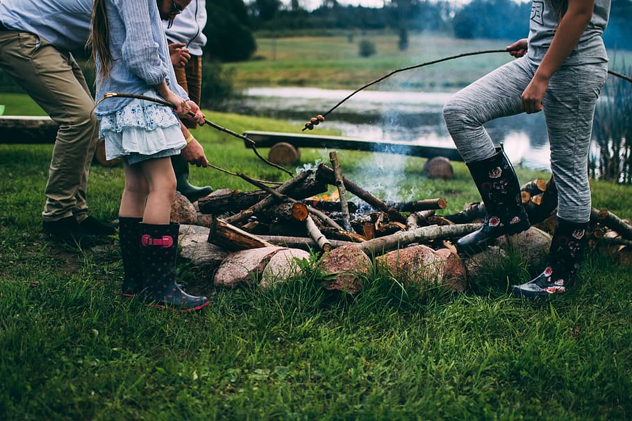 family camping near body of water during daytime, group of people in front of bonfire HD wallpaper