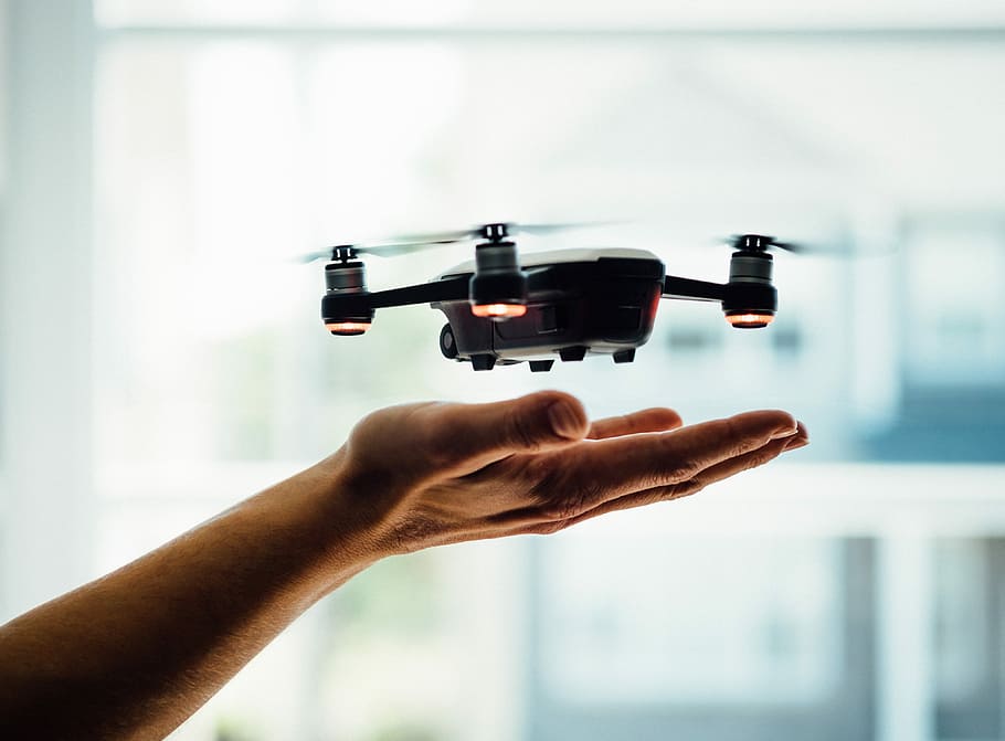 turned on black quadcopter drone, human hand trying to reach on black and white quadcopter drone HD wallpaper