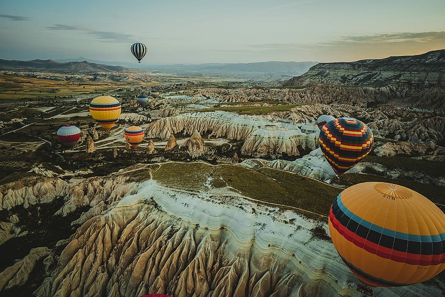 assorted-color hot air balloons on mid-air during orange sunset, hot air balloons flying over white and brown rock formations HD wallpaper