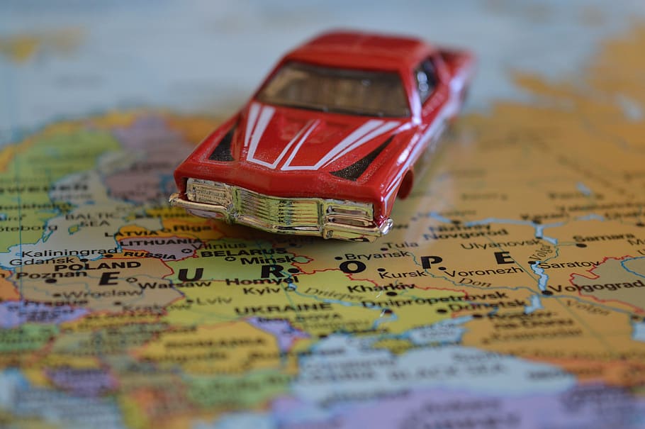 vintage red die-cast toy car on political map, journey, europe