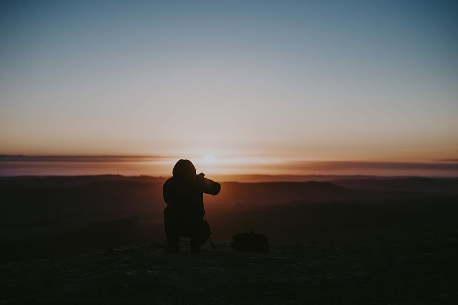 Getting that sunrise shot, person sitting on mountain silhouette photography HD wallpaper