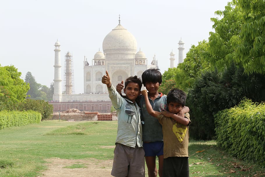 three childrens standing near Taj mahal during daytime, indians