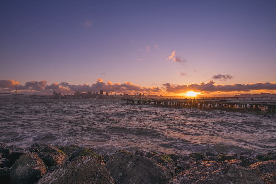 ocean waves hammering rock boulders, body of water waving during sunset HD wallpaper