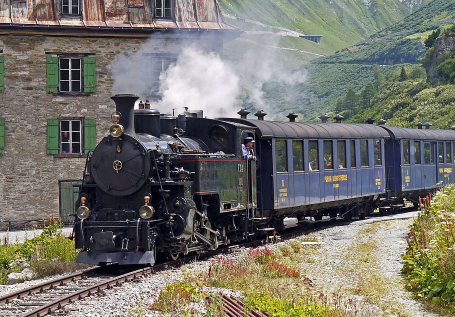black and blue train near gray concrete house, steam railway furka-bergstrecke