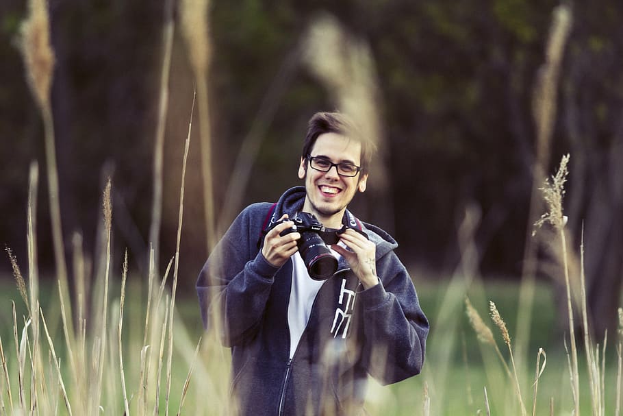 man holding DSLR camera standing in field, photographer, young HD wallpaper