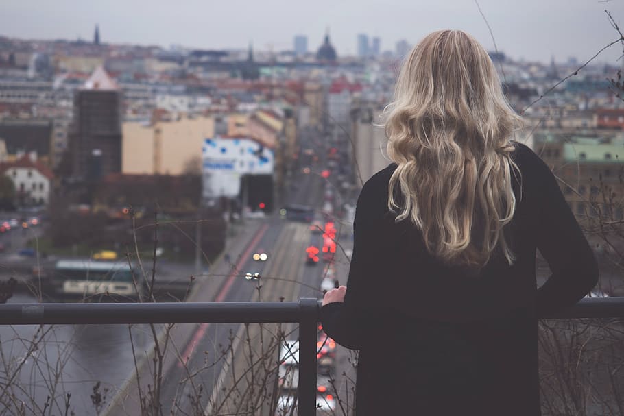 woman standing in front of black metal rail facing road and buildings HD wallpaper