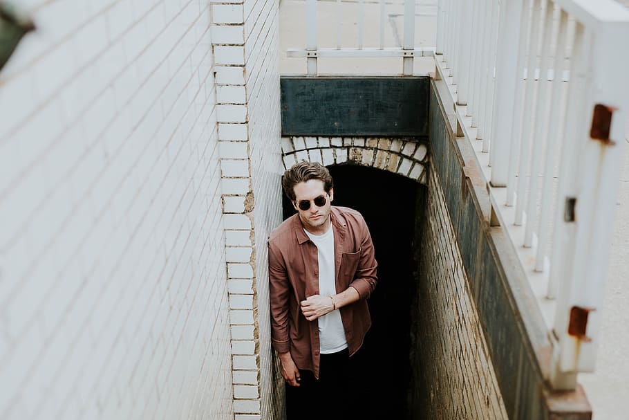 man leaning on wall while standing on stairs underground, man wearing brown sport shirt standing on stairs at daytime HD wallpaper