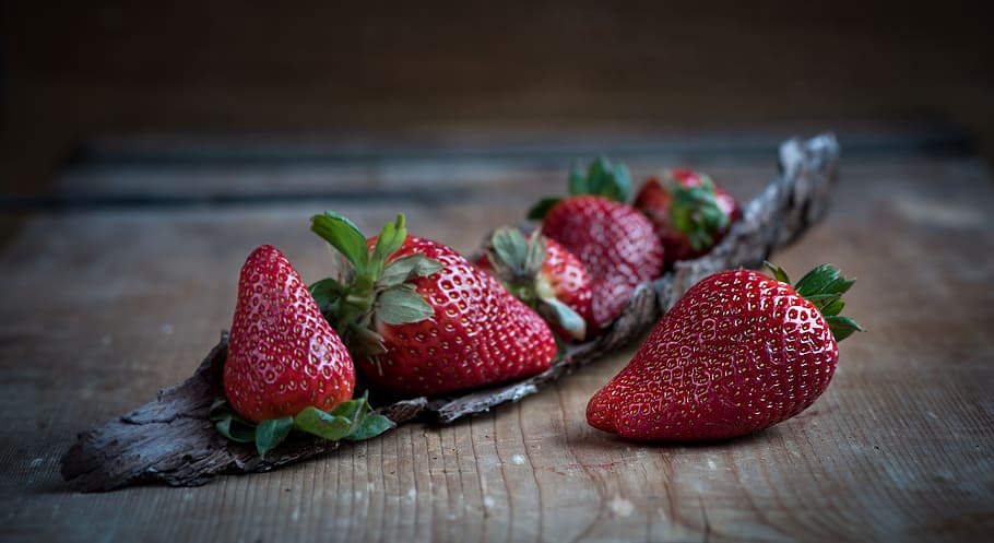 close up photo of strawberries on brown wooden table, red, ripe