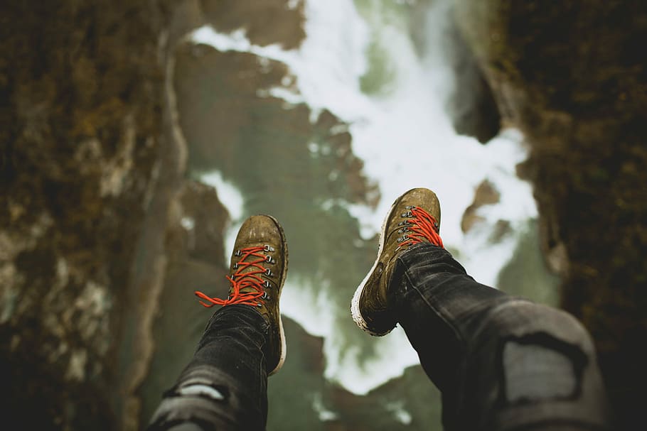 person sitting on cliff, shallow focus photography of person wearing black denim pants and grey-and-orange shoes, HD wallpaper