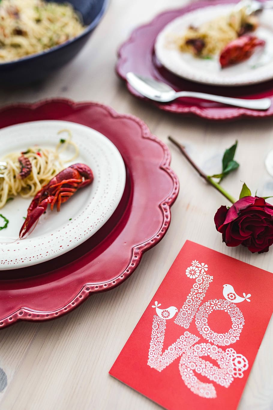 Fancy dinner with seafood pasta, crayfish and red wine by the table decorated with roses HD wallpaper