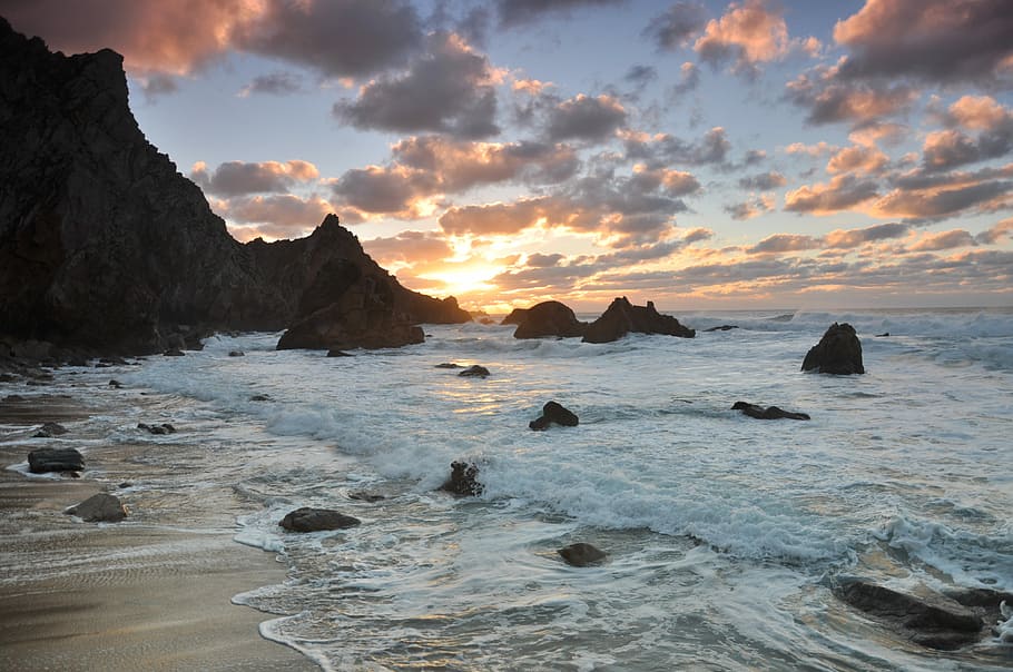 Awesome sunset, body of water near rock formation under cloudy sky at daytime HD wallpaper